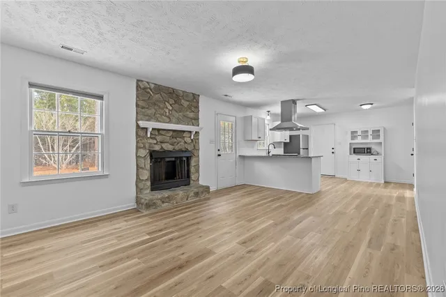 a view of empty room with kitchen and fireplace