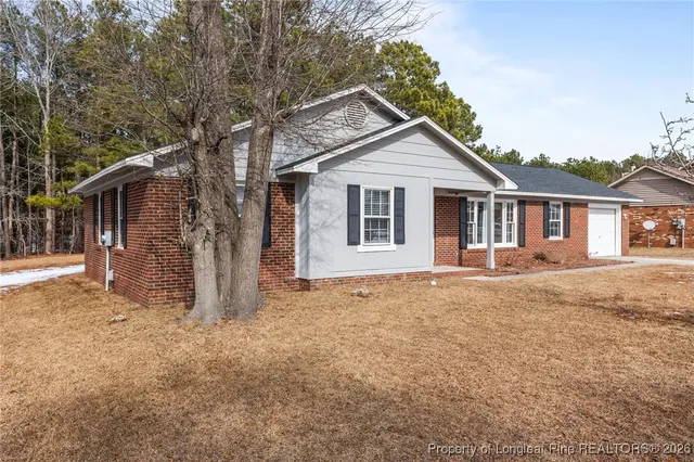 a view of a house with a yard and large tree