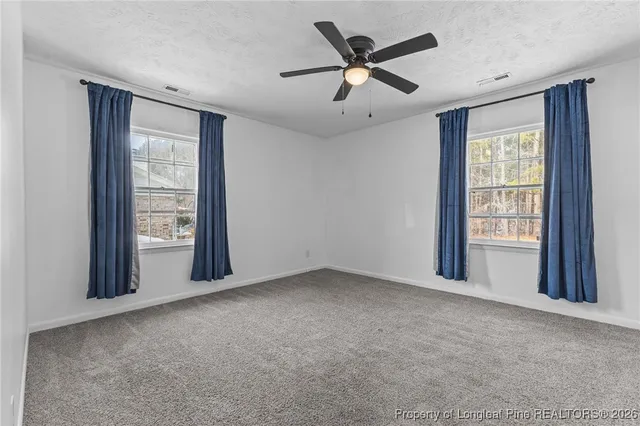 an empty room with windows and fan