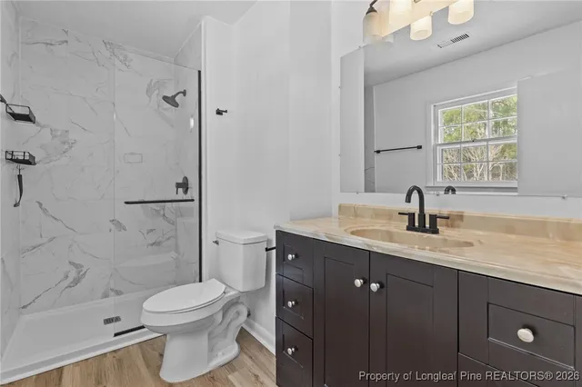 a bathroom with a granite countertop sink a toilet and shower