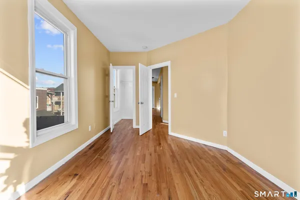 a view of an empty room with wooden floor and a window