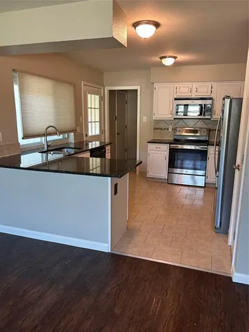a kitchen with stainless steel appliances wooden floor and a counter top space