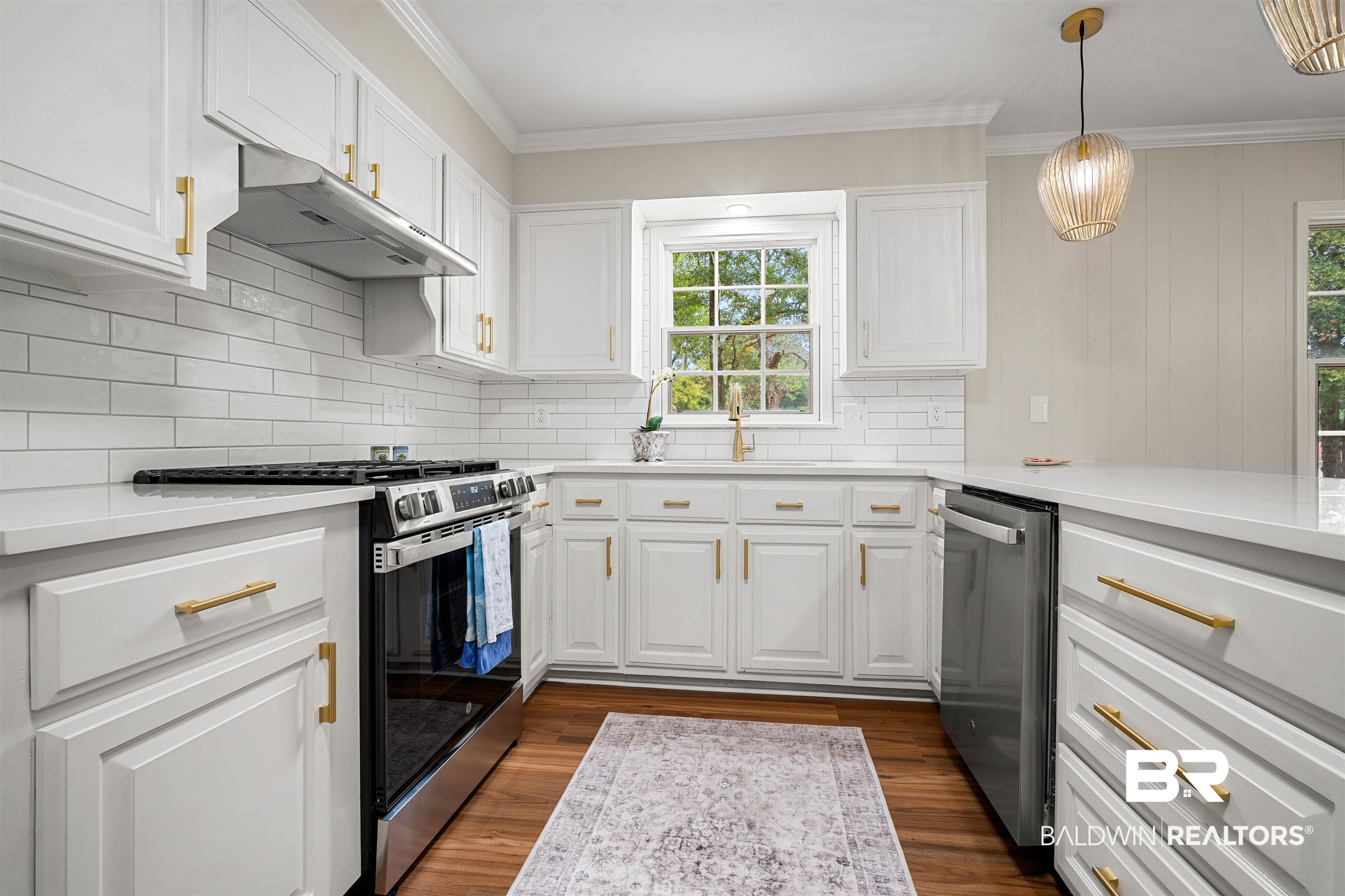 3050 Lacoste Road Mobile, AL 36618 - Photo 10 of 30 Kitchen featuring stainless steel appliances, white cabinetry, under cabinet range hood, dark wood-type flooring, and crown molding