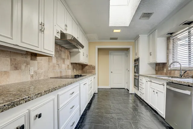 a large kitchen with stainless steel appliances granite countertop a sink and cabinets