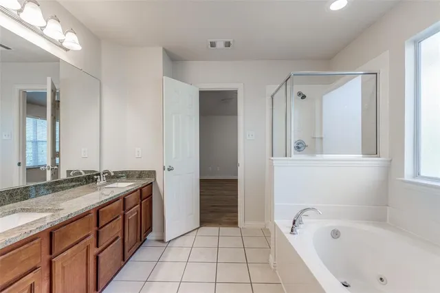 a spacious bathroom with a granite countertop sink a mirror and a bathtub