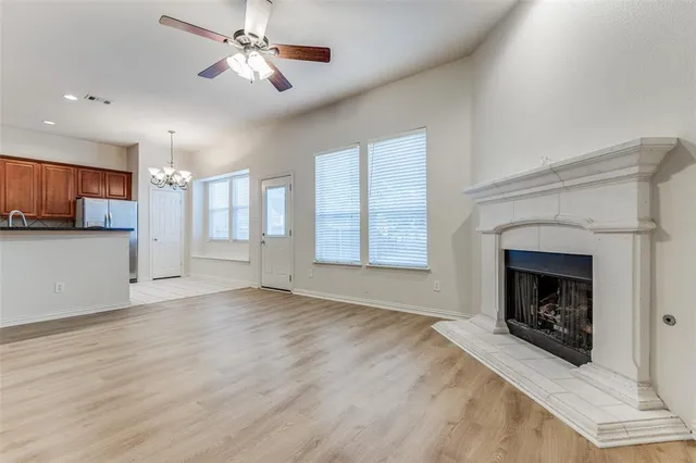 a view of a livingroom with a fireplace a ceiling fan and windows