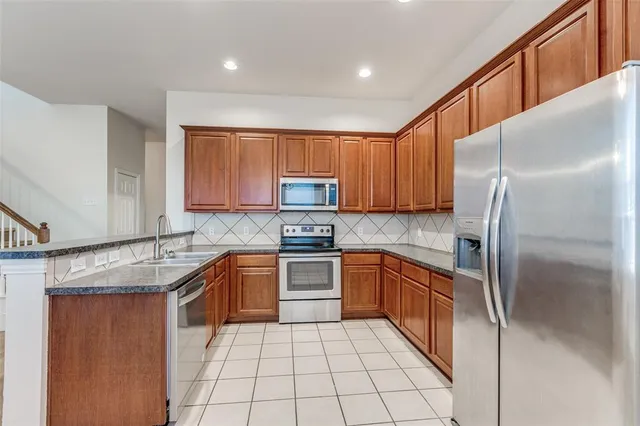 a kitchen with stainless steel appliances granite countertop a sink and dishwasher a refrigerator with wooden cabinets