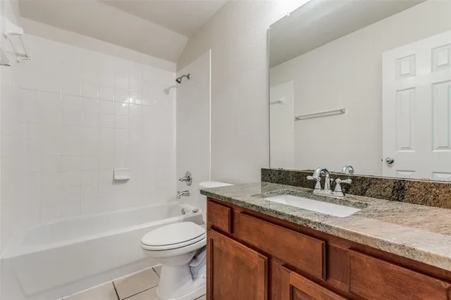 a bathroom with a granite countertop toilet sink and mirror