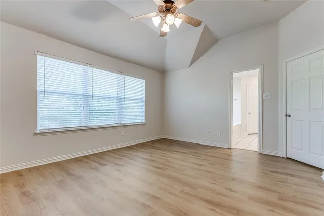 an empty room with wooden floor chandelier fan and windows