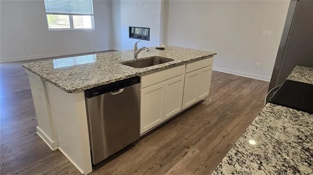 a kitchen with granite countertop sink stove and cabinets