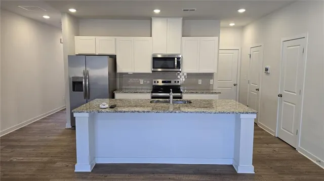 a kitchen with kitchen island stainless steel appliances a sink stove and refrigerator