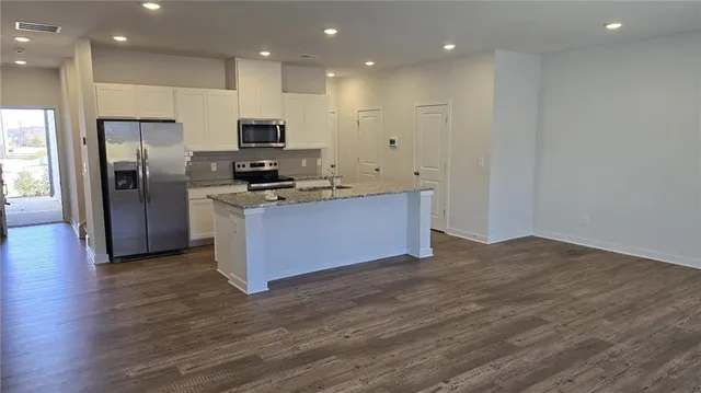 a kitchen with stainless steel appliances granite countertop a stove a refrigerator a sink and a microwave