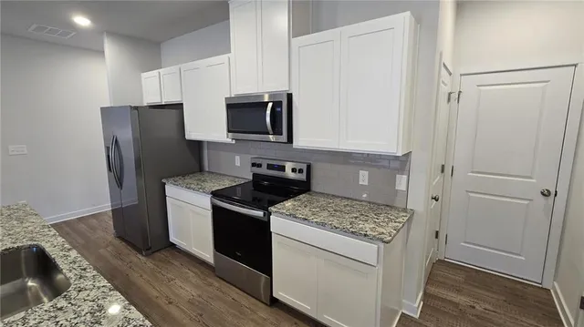 a kitchen with stainless steel appliances granite countertop a refrigerator stove and sink