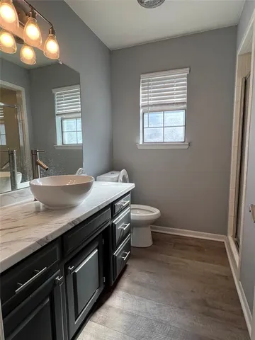 a bathroom with a granite countertop sink a toilet and a window