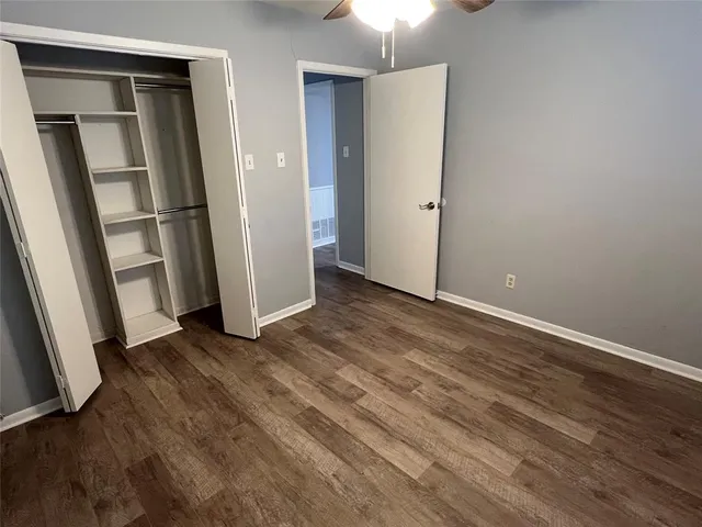 an empty room with wooden floor and a ceiling fan