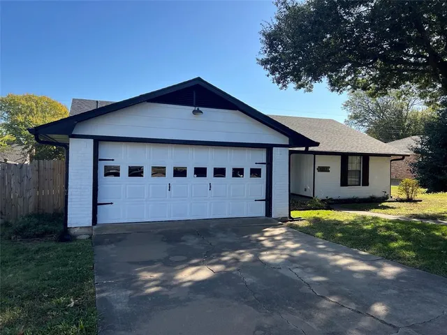 a front view of a house with a garden and trees