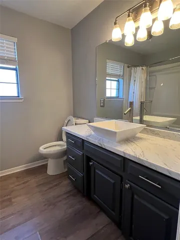 a bathroom with a granite countertop sink a toilet and a mirror