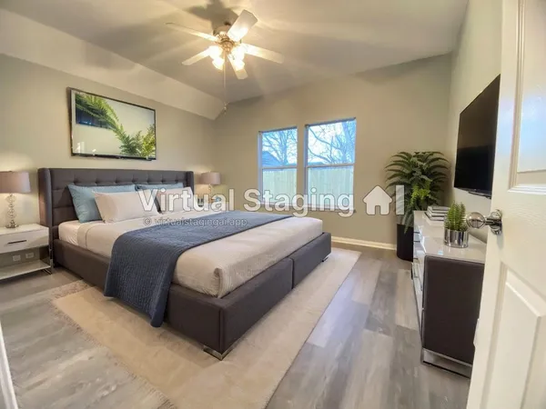 a spacious bedroom with a large bed a flat tv screen and a chandelier