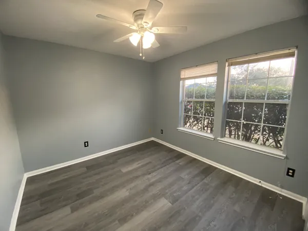 an empty room with wooden floor and windows