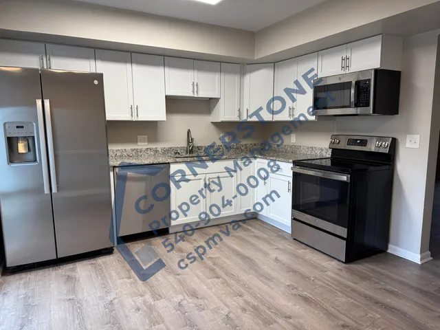 a kitchen with stainless steel appliances granite countertop a stove a refrigerator and a microwave