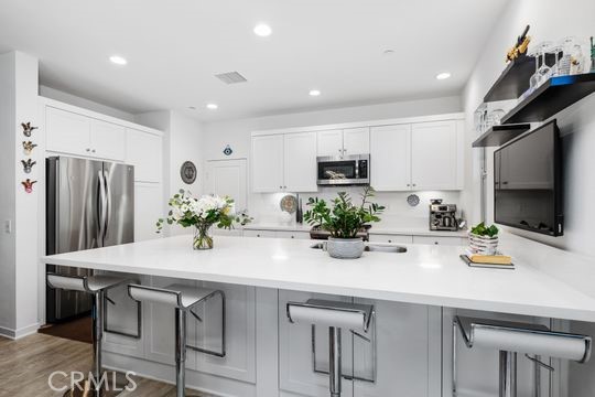 165 Frame Irvine, CA 92618 - Photo 10 of 37 a kitchen with stainless steel appliances a table chairs refrigerator and microwave