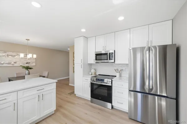 a kitchen with stainless steel appliances white cabinets and wooden floors