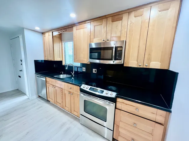a kitchen with stainless steel appliances a stove microwave and sink