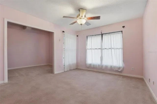 an empty room with a ceiling fan and window