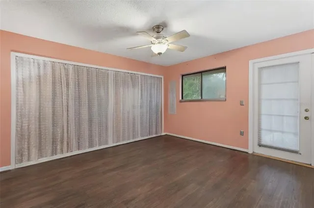 an empty room with wooden floor chandelier fan and windows