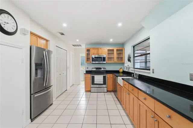 a large kitchen with stainless steel appliances granite countertop a refrigerator and a stove top oven