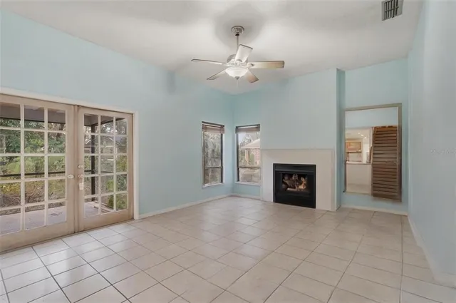 an empty room with windows fireplace and fans