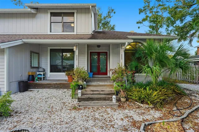a view of a house with potted plants and a large tree
