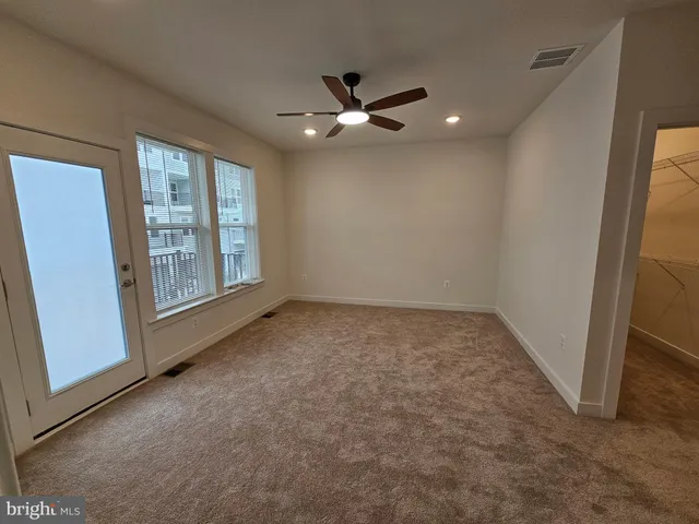 an empty room with windows and fan