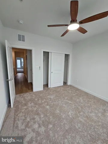 an empty room with windows and ceiling fan