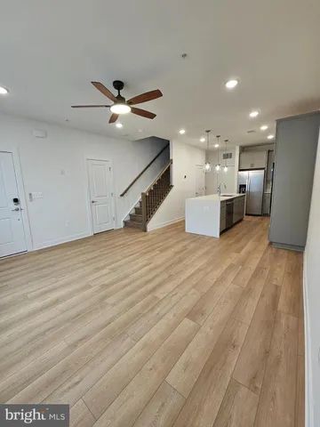 a view of a room with kitchen island stainless steel appliances wooden floor and living room view