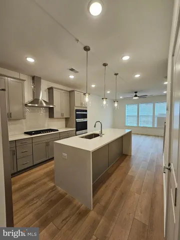 a large kitchen with kitchen island a stove a sink a refrigerator and a dining table with wooden floor