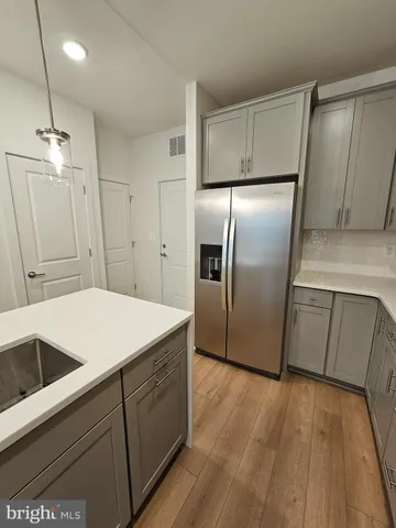 a kitchen with kitchen island a counter top space wooden floor and stainless steel appliances