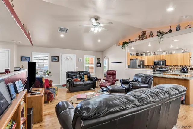 a living room with furniture kitchen view and a chandelier