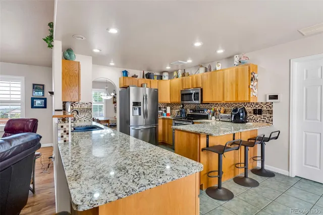 a kitchen with stainless steel appliances granite countertop a refrigerator a stove and a sink