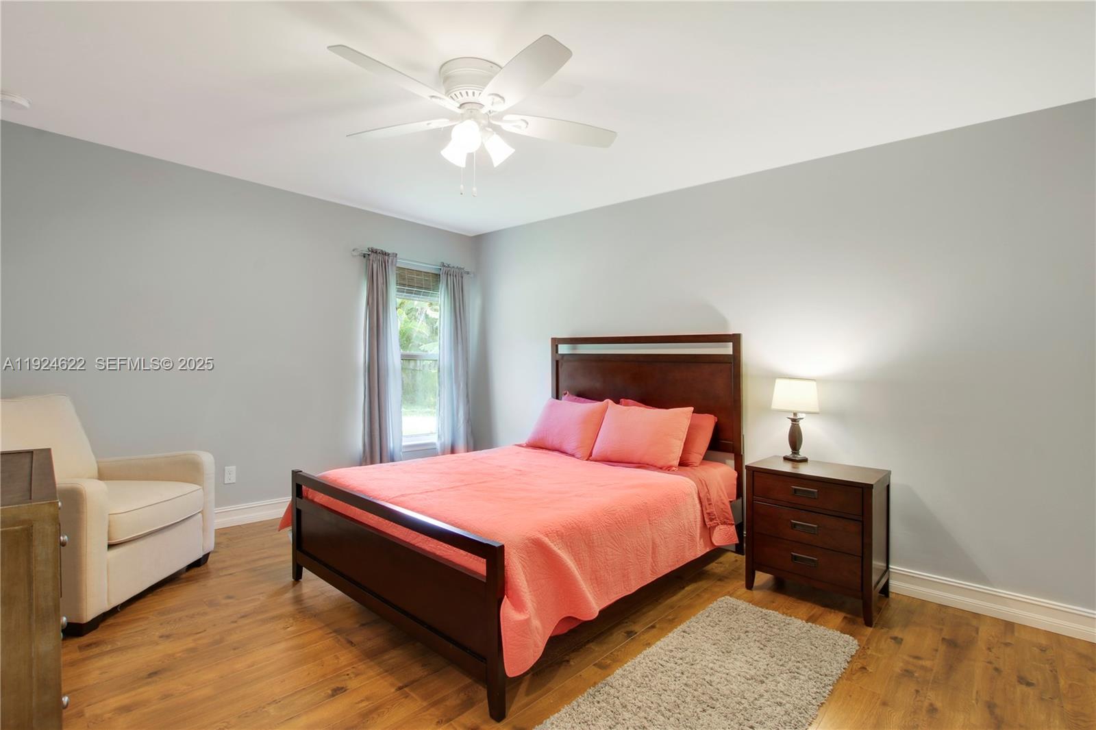 9155 Southeast Athena Street Hobe Sound, FL 33455 - Photo 13 of 25 a bedroom with a bed and a chandelier