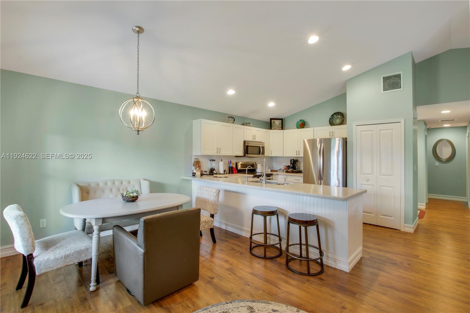 9155 Southeast Athena Street Hobe Sound, FL 33455 - Photo 6 of 25 a kitchen with a dining table chairs refrigerator and cabinets