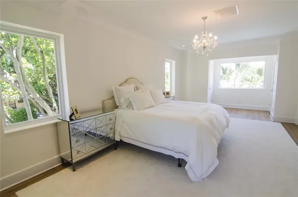 a spacious bedroom with a bed chandelier and window