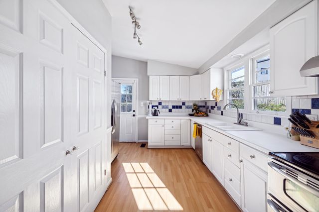 a kitchen with stainless steel appliances granite countertop a sink cabinets and wooden floor