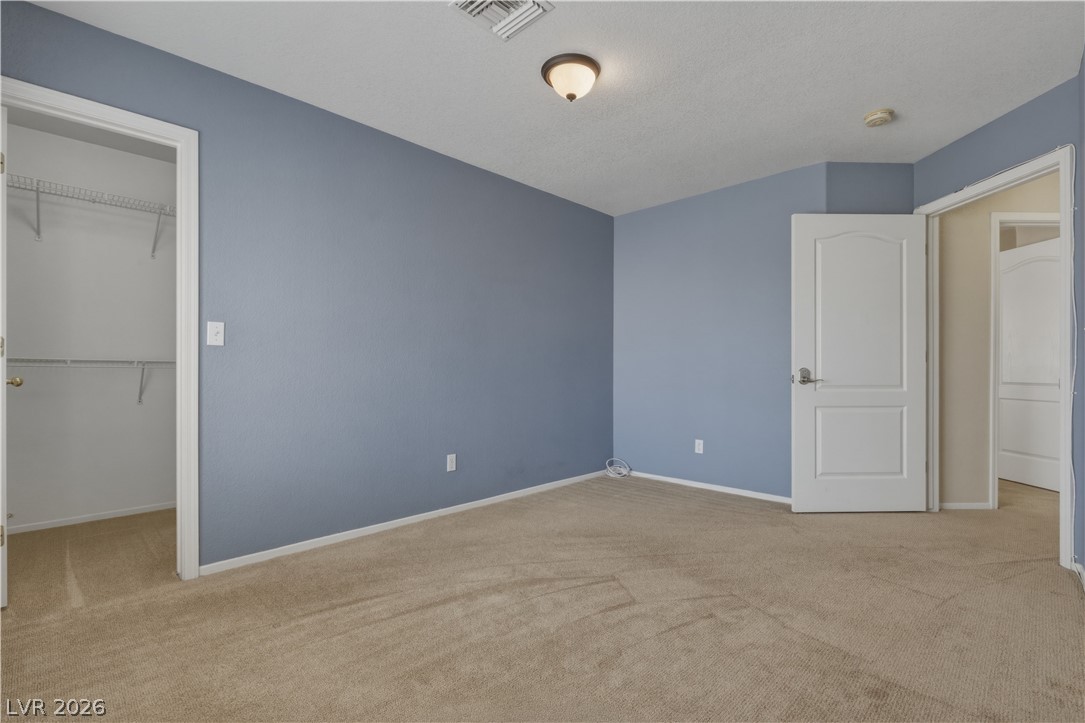 29 Olive Tree Henderson, NV 89074 - Photo 44 of 60 This spacious bedroom offers comfortable carpeting and a convenient walk-in closet.