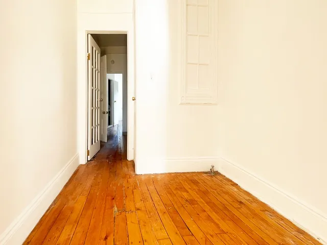 a view of a room with wooden floor and a white wall