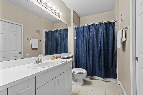 a bathroom with a toilet a sink a mirror and shower curtain