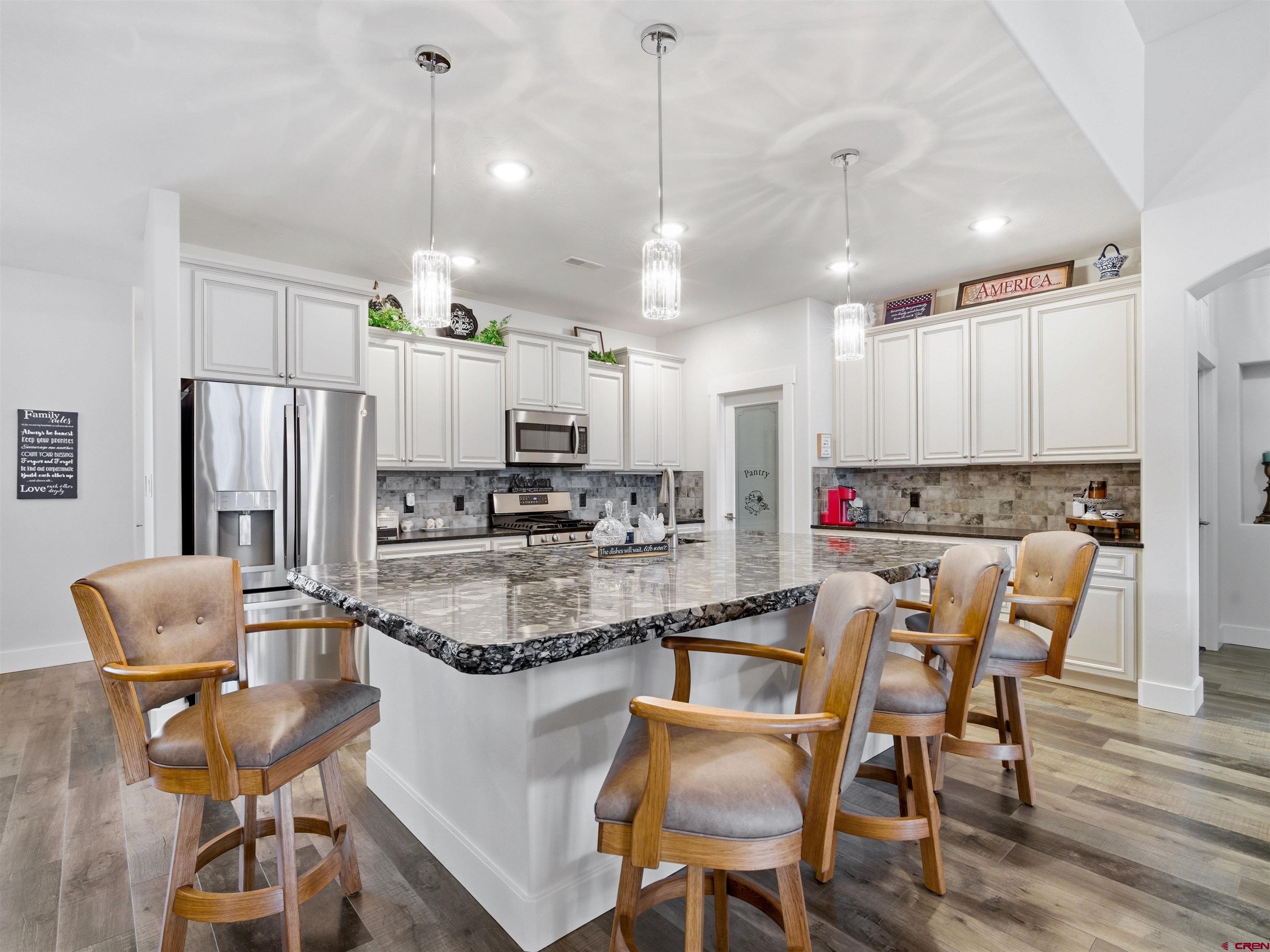 1223 Eagle Way Fruita, CO 81521 - Photo 9 of 34 a kitchen with stainless steel appliances granite countertop a table chairs refrigerator and microwave