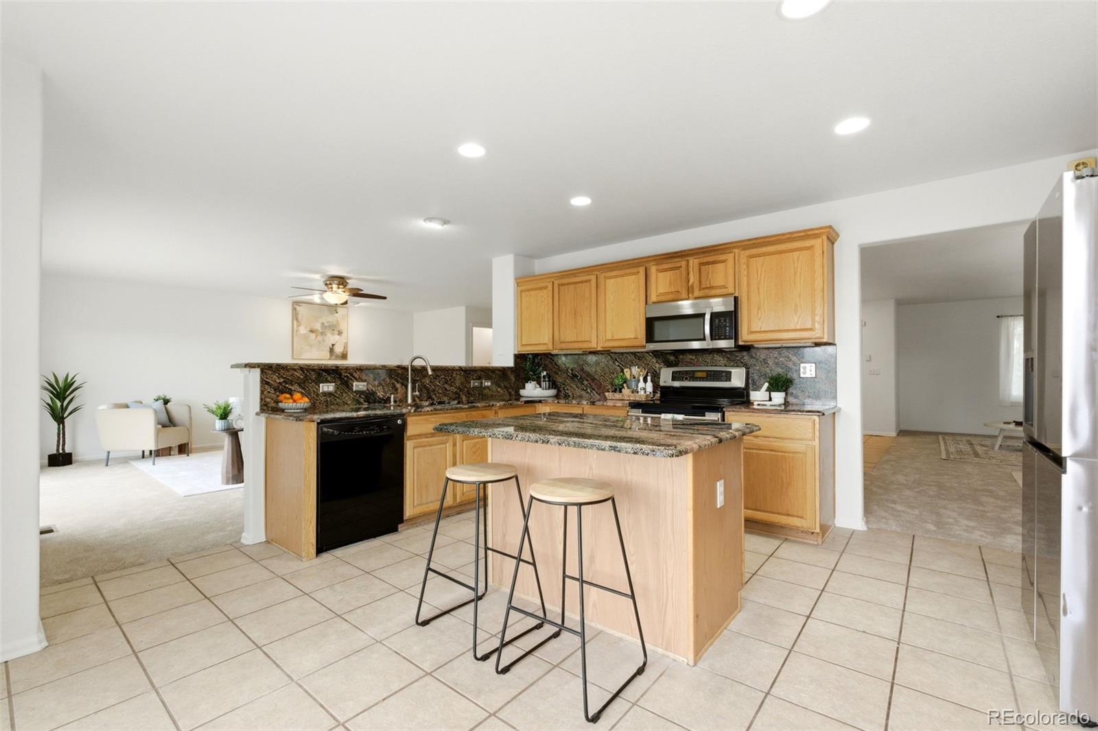 3033 East 108th Drive Northglenn, CO 80233 - Photo 12 of 50 a kitchen with stainless steel appliances granite countertop a stove a sink a refrigerator and a microwave