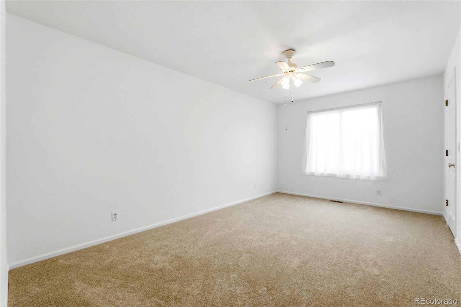 3033 East 108th Drive Northglenn, CO 80233 - Photo 28 of 50 an empty room with a window and ceiling fan