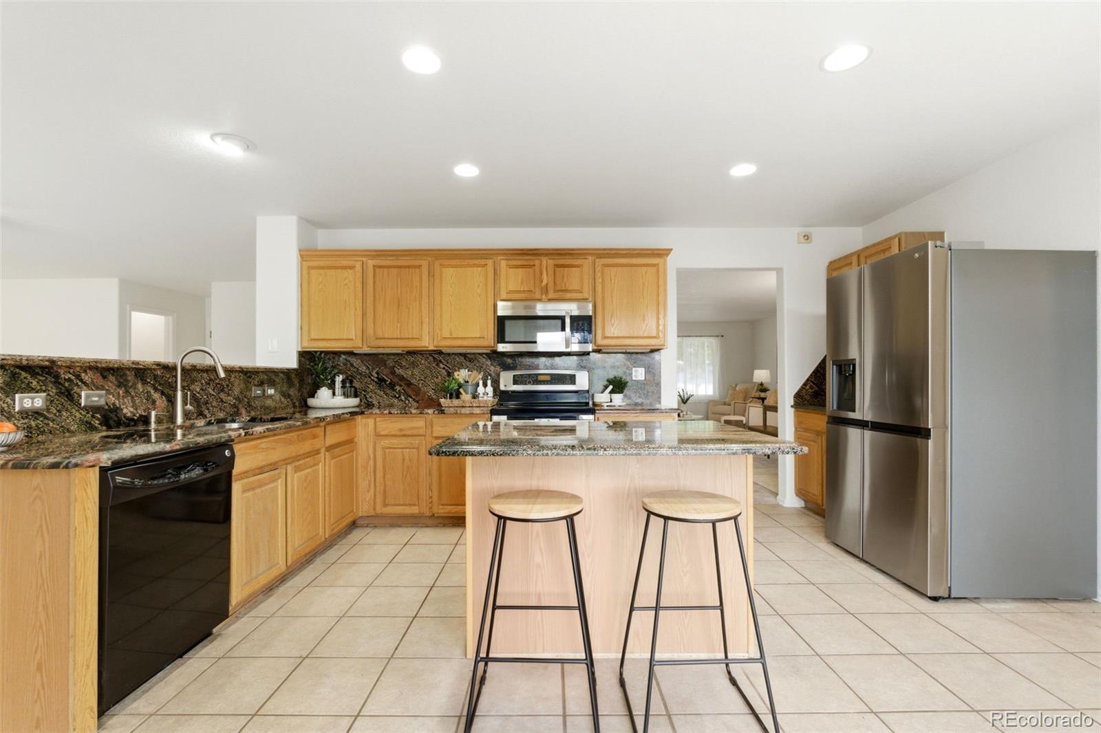 3033 East 108th Drive Northglenn, CO 80233 - Photo 9 of 50 a kitchen with stainless steel appliances granite countertop a refrigerator and a stove top oven